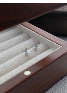 Macro shot of silver cherry earrings with white pearls and crystals in a wooden box