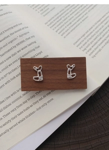 Detail of S999 silver textured heart studs with zircon on wood and book background