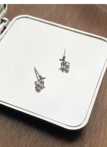 Macro shot of S999 sterling silver cherry pearl earrings reflecting on a mirror surface