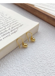 Dettaglio macro di orecchini a goccia dorati su un libro per un look di lusso elegante