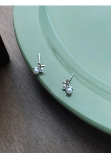Detail of silver S999 cherry pearl stud earrings with zircon on a green ceramic plate