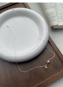 Detail of silver S925 necklace with polished ring and zircon star pendant on a ceramic tray