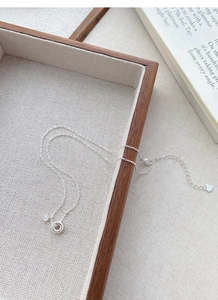 Detail view of S925 sterling silver necklace with zircon pendant on a linen tray