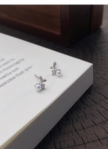 Macro detail of cherry-shaped S999 silver earrings with white pearl and sparkling zircon