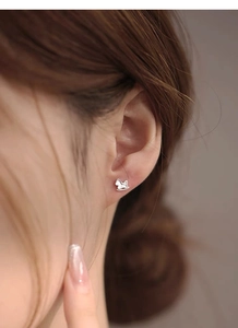 Close-up of minimalist S999 silver rocking horse stud earring worn on earlobe