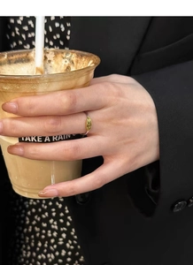 Minimalist gold ring with irregular oval decoration shown in a daily lifestyle hand pose