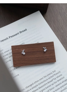 Macro shot of silver cherry stud earrings with pearls and crystals on wood