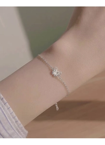 Dettaglio del bracciale in argento S999 con farfalla traforata e testurizzata al polso femminile