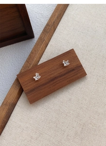 Detailed close-up of S999 sterling silver rocking horse stud earrings on a wood display