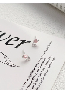 Makroaufnahme von rosa Tulpen-Ohrsteckern mit Zirkon-Blättern auf einer Karte