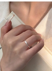 Detailed close-up of a sterling silver minimalist fish ring worn on a finger