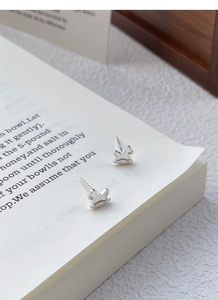 Macro shot of silver rocking horse stud earrings with polished finish and bead details