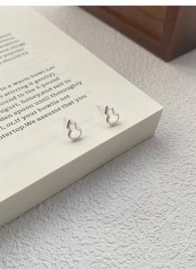 Détail de boucles d'oreilles gourde évidée en argent S999 avec bord perlé sur un livre
