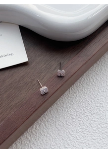 Macro detail of S999 silver aurora clover earrings with opal-style stones on wood