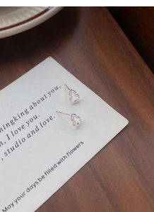 Détail de boucles d'oreilles cœur en argent avec oxydes de zirconium sur carte blanche