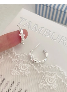 Detail of S925 silver bow earrings with bamboo texture and twisted rope design