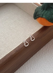 Détail de boucles d'oreilles gourde en argent S999 avec filigrane sur plateau