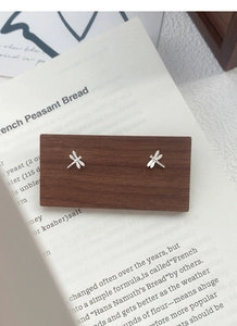 Detailed macro view of S999 sterling silver dragonfly stud earrings on a wooden display