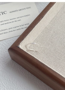 Detail of minimalist silver ring with fine texture and tiny zircon on a wooden box