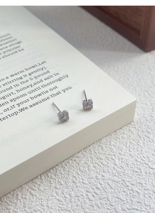 Macro detail of silver four-leaf clover earrings with lavender opal stones on a book
