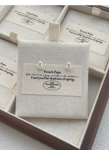 Gros plan de boucles d'oreilles gourde évidées en argent S999 sur carte en tissu blanc