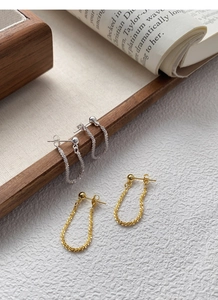 Detailed macro view of S925 silver and gold U-shaped earrings with shimmering sand chains