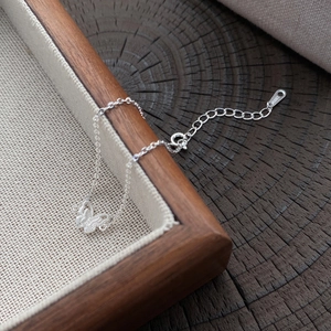 Collana con ciondolo a farfalla in argento sterling S925 minimalista su fondo legno scuro