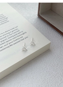 Detailed macro view of S999 sterling silver dragonfly stud earrings on book pages