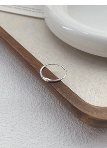 Macro detail of silver minimalist fish ring with crystal on linen display tray
