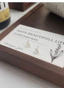 Detailed close-up of S999 sterling silver dragonfly earrings on an artistic display card