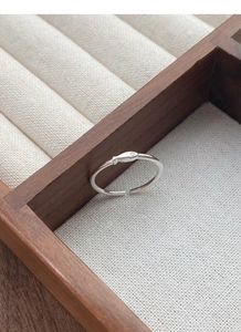 Macro shot of minimalist silver fish open ring with sparkling zircon in a wooden tray