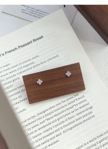 Macro shot of S999 silver four-leaf clover earrings with aurora blue gemstones on wood