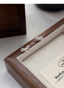 Gros plan de boucles d'oreilles fleurs en argent S999 avec pierres bleues sur lin