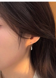 Close-up of a minimalist silver teardrop earring on model with polished finish