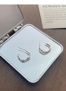 Macro detail of S925 sterling silver bamboo hoop earrings with hallmark on silver mirror
