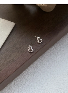 Vue détaillée de boucles d'oreilles gourde évidées en argent sterling S999 sur bois sombre