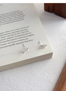 Detailed view of silver swallow stud earrings placed on a book for a minimalist look