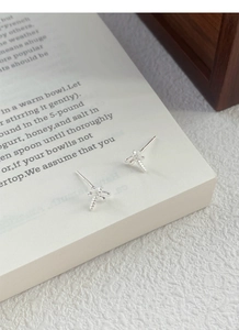 Detailed view of S925 sterling silver dragonfly stud earring on a vintage book page