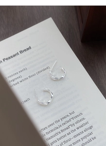 Close-up of S925 sterling silver bow-knot hoop earrings with bamboo texture on a book