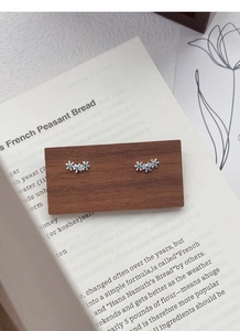 Détail macro de boucles d'oreilles trois fleurs en argent avec pierre bleue sur bois