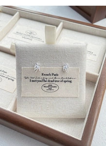 Detail of silver swallow stud earrings with fine wing texture on a cotton display card