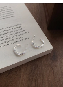 Detail shot of silver S925 sterling silver bow earrings with textured bamboo design