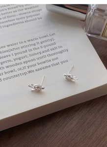 Detailed close-up of S999 sterling silver swallow stud earrings placed on an open book