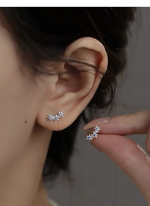 Gros plan de boucles d'oreilles fleurs en argent S999 avec zircons bleus sur le lobe