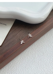 Macro shot of S999 sterling silver dragonfly earrings on a vintage wooden tray