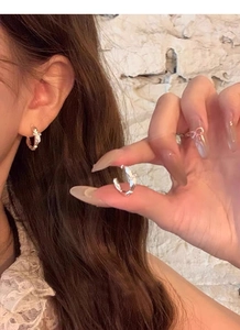 Close-up of elegant S925 silver bow knot hoop earrings worn on ear with soft lighting