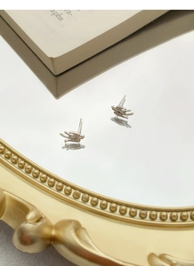Macro shot of silver swallow bird stud earrings reflecting on a vintage circular mirror