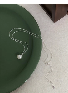 Détail du collier en argent S999 avec perle blanche sur une assiette en céramique