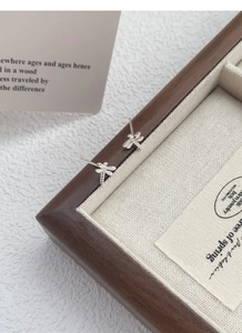 Close-up of S925 sterling silver dragonfly stud earrings on a vintage wooden jewelry box
