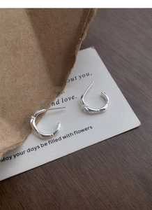 Detail shot of silver S925 earrings with unique bamboo texture on a stylish display card